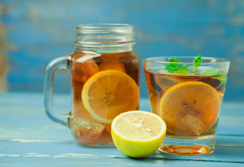 Iced tea with lemon slices and mint on wood background
