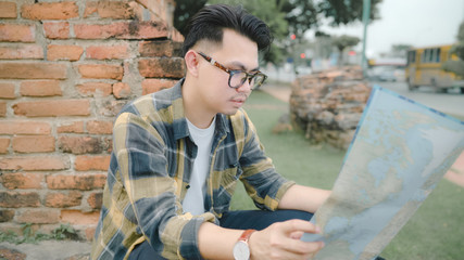 Fototapeta na wymiar Traveler Asian man direction and looking on location map while spending holiday trip at Ayutthaya, Thailand, backpacker male enjoy journey in traditional city. Lifestyle men travel concept.