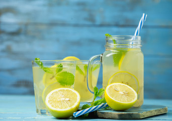 Lemonade or mojito cocktail with lemon and mint on wood background