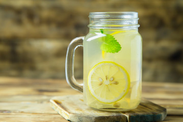 Lemonade or mojito cocktail with lemon and mint on wood background