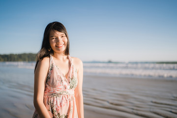 Fototapeta na wymiar Young Asian woman feeling happy on beach, beautiful female happy relax smiling fun on beach near sea when sunset in evening. Lifestyle women travel on beach concept.