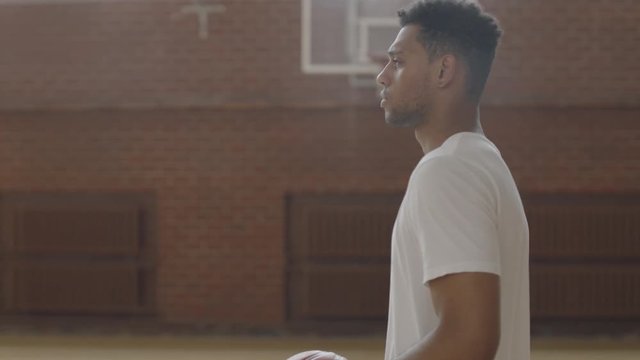 TRACKING young confident African American black college basketball player in generic uniform walking with a ball, indoor arena. Shot on ARRI Alexa Mini, 4K RAW graded footage