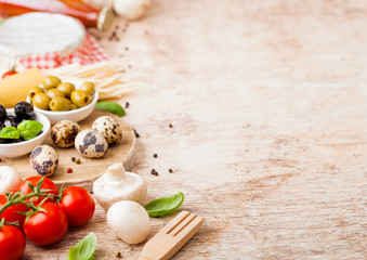 Homemade spaghetti pasta with quail eggs with bottle of tomato sauce and cheese on wooden background. Classic italian village food. Garlic, champignons, black and green olives, oil and spatula.