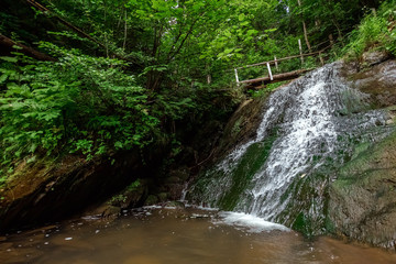 Small green forest waterfall in the cave mountains, cascades on a mountain river. The concept of active holidays, holidays