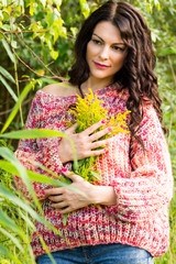The woman in a knitted pullover poses against the background of the nature