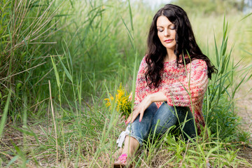 The woman in a knitted pullover poses against the background of the nature
