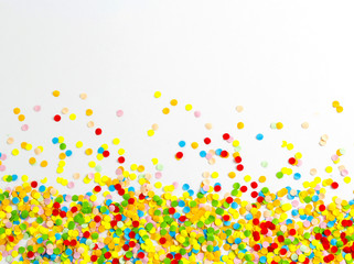 Confetti scattered in different colors on the white background. Festive confetti. The decor for the party.