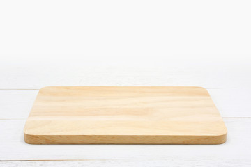 Empty rectangle wooden cutting board on white wooden table.