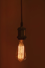 Hanging modern lamp bulb against brown background