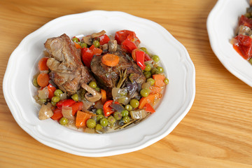 Plate with meat and garnish prepared in multi cooker on wooden table