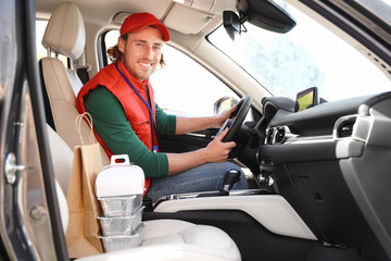 Male courier with orders in car. Food delivery service