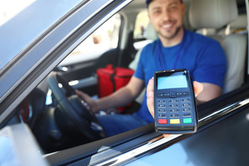 Male courier with terminal in car. Food delivery service