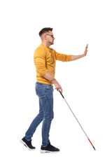 Blind man in dark glasses with walking cane on white background