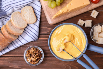 Fototapeta na wymiar Flat lay composition with pot of cheese fondue and products on wooden table