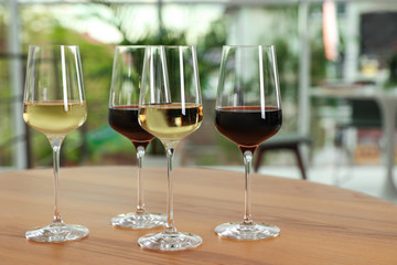 Glasses with different wines on table against blurred background