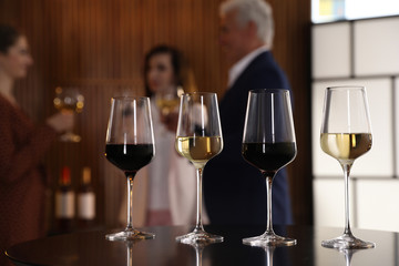 Glasses of different wines on table against blurred background