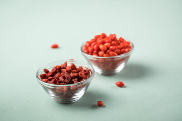 Frische und getrocknete Goji-Beeren Superfood in Glas Schale auf Mint Grün Pastell Hintergrund
