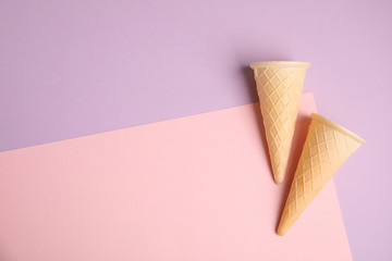 Empty wafer ice cream cones on color background, flat lay. Space for text