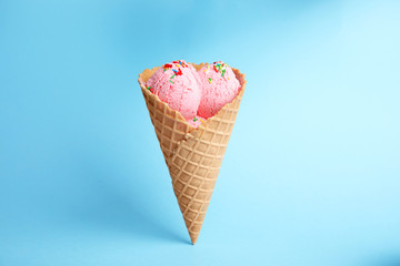 Delicious ice cream in wafer cone on blue background