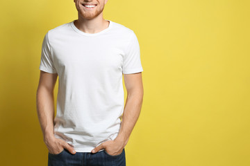 Young man wearing blank t-shirt on yellow background, closeup. Mockup for design