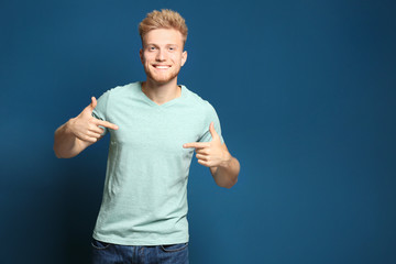 Naklejka premium Young man wearing blank t-shirt on blue background. Mockup for design