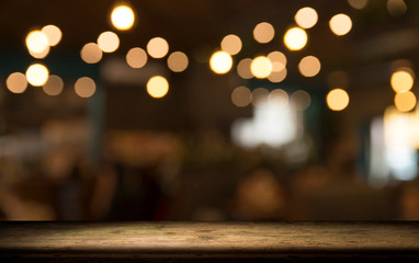 Empty wood table top on blur light gold bokeh of cafe restaurant in dark background