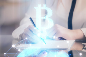 Cryptocurrency hologram over woman's hands writing background. Concept of blockchain. Double...