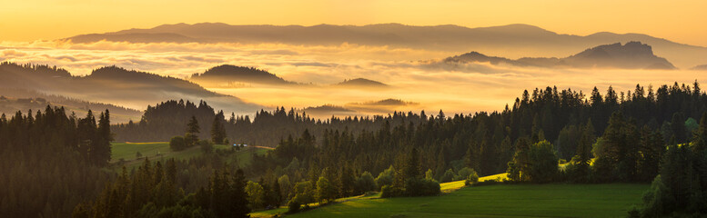 A beautiful mountain view. Mountains and green hills emerging from the morning mists illuminated by the rising sun. A view from the top of the Czarna Góra mountain in Poland