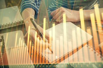 Fototapeta premium Financial chart drawn over hands taking notes background. Concept of research. Double exposure