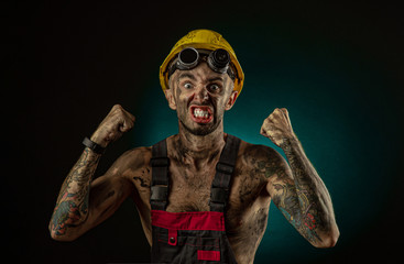 Portrait of happy smiling coal miner with his arms crossed against a dark background