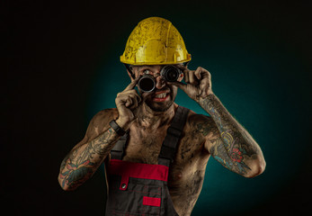 Portrait of happy smiling coal miner with his arms crossed against a dark background