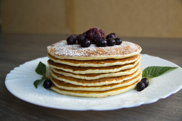 Pancake with powdered sugar, blueberries and blackberries on a plate