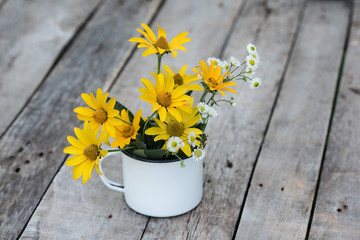 Yellow flower in the cup on the wooden table