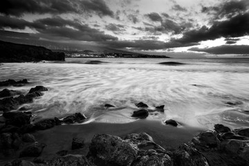 Black and white dramatic beautiful sunrise at the beach with ocean stretch waves and great sky with clouds. Long exposure water effect and nobody out there - wild outdoor nature