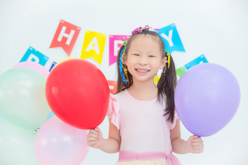 Fototapeta na wymiar Little asian girl holding balloons and smiling in her birthday party