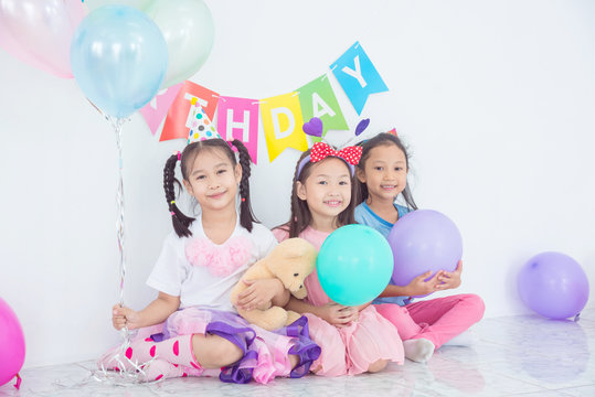 Colorful portrait of three happy asian girls sitting together in celebration of birthday and smiling.