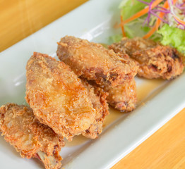 Fried chicken, fish sauce and lettuce, carrots, cauliflower, slide in a white plate on a wooden table