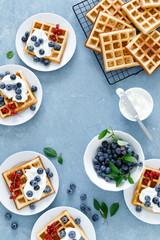 Traditional belgian waffles with cream cheese and fresh blueberry on blue background, top view