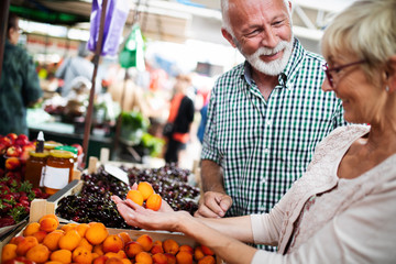 Happy senior couple with basket at the local market
