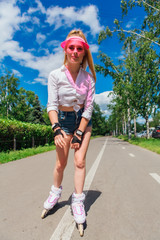 Portrait of an emotional girl in a pink cap visor and protective gloves for rollerblades and...