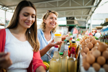 Young woman buying vegetable on stall at the market