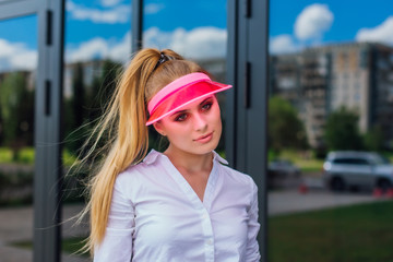 Portrait of an emotional girl in a pink cap visor and protective gloves for rollerblades and...