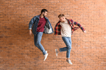 Obraz na płótnie Canvas Jumping young men near brick wall