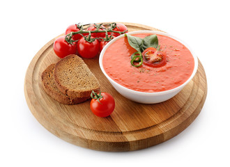 Board and bowl of tasty tomato cream soup on white background