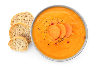 Bowl of tasty carrot cream soup and bread on white background