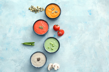 Bowls of different tasty cream soups on color background