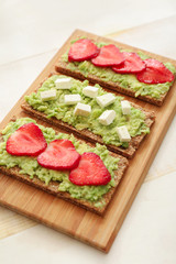 Tasty avocado toasts on wooden board