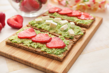 Tasty avocado toasts on wooden board