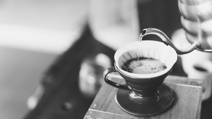 barista pouring hot water on coffee ground, home brewing process, black and whit tone