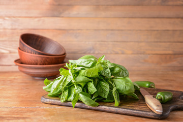 Cutting board with fresh green basil on wooden table